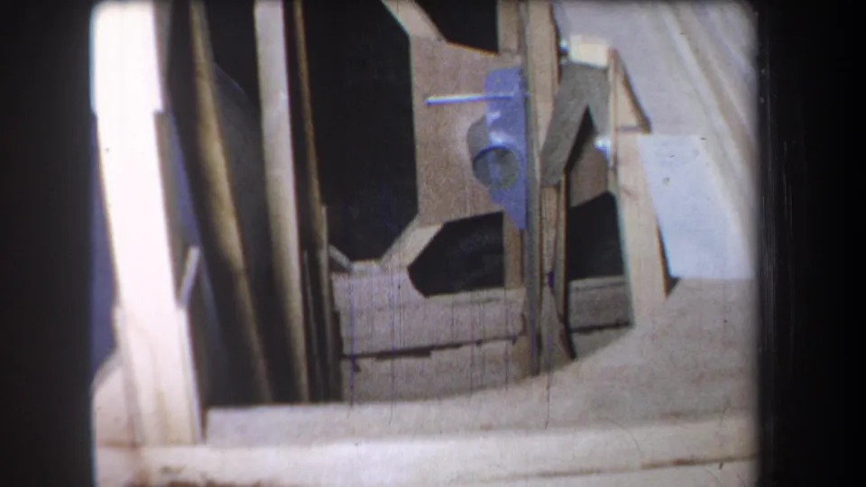 1965 Volmer Yucaipa frame showing close wooden construction details, including vertical supports, angled board edges, dark gaps, and a blue hardware piece.