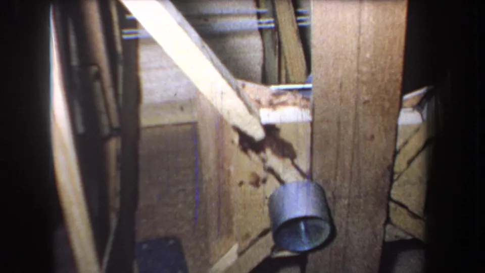1965 Yucaipa-area 8mm frame showing aged wooden door boards, diagonal bracing, a round metal fixture, stains, and shadowed edges.