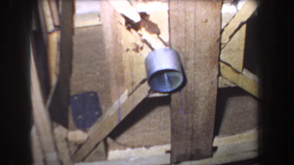 1965 Yucaipa-area frame with rough wooden door boards, diagonal bracing, a round metal fixture, stained wood, and visible 8mm film wear.