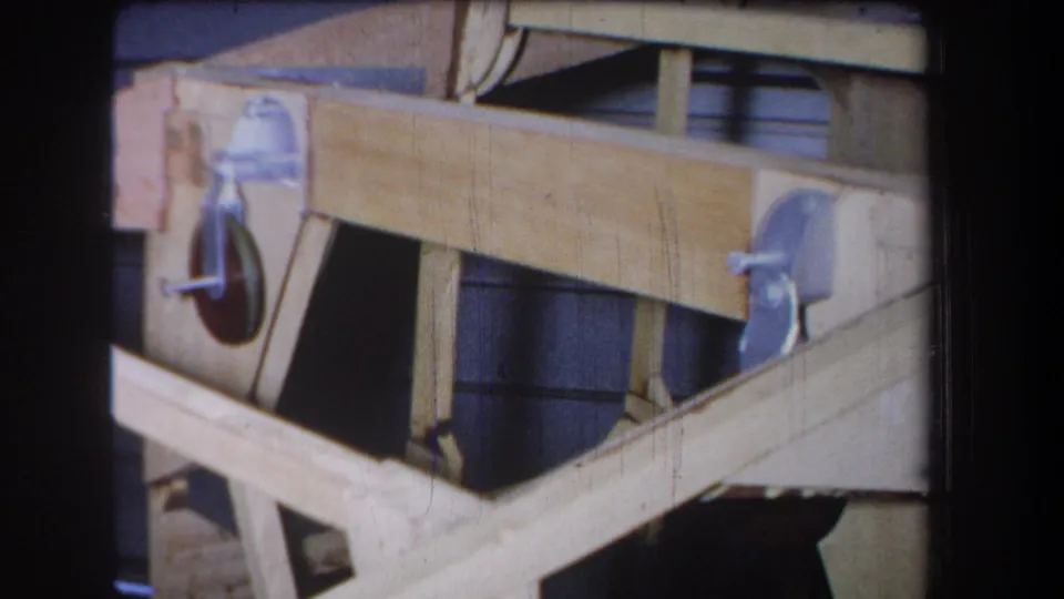1965 Yucaipa-area home-movie frame showing a handmade wooden assembly with multiple metal pulley wheels and diagonal supports.
