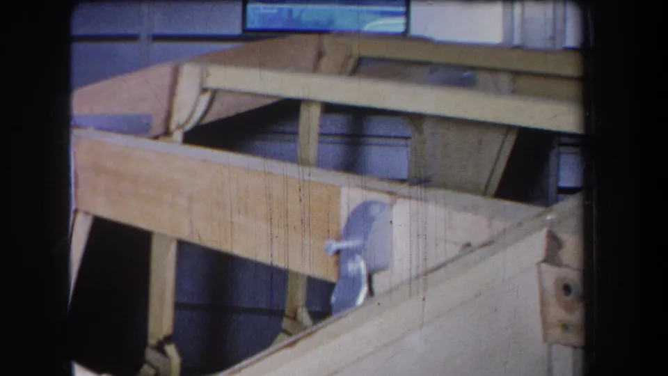 1965 8mm frame from Yucaipa-area footage showing the side of a wooden pulley system, with metal hardware and visible film wear.
