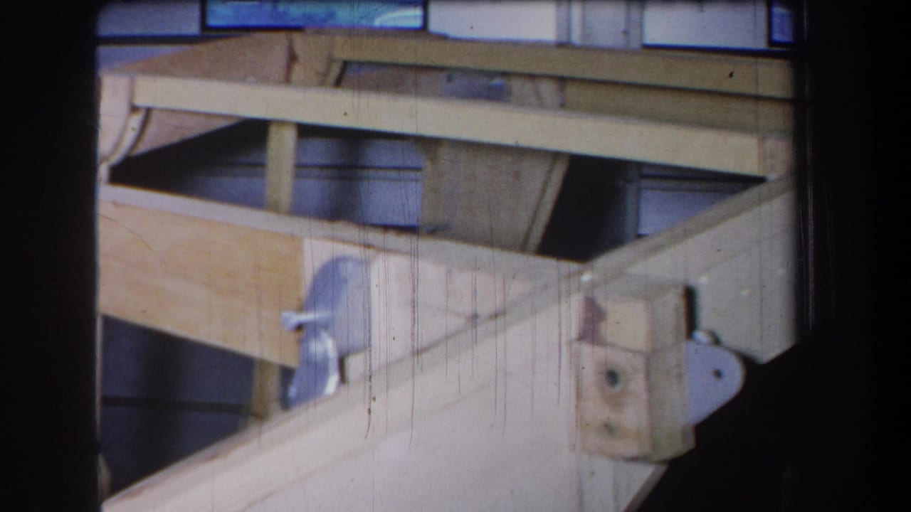 1965 Yucaipa home-movie frame showing pale wooden structural members, a diagonal brace, and metal fastening hardware.