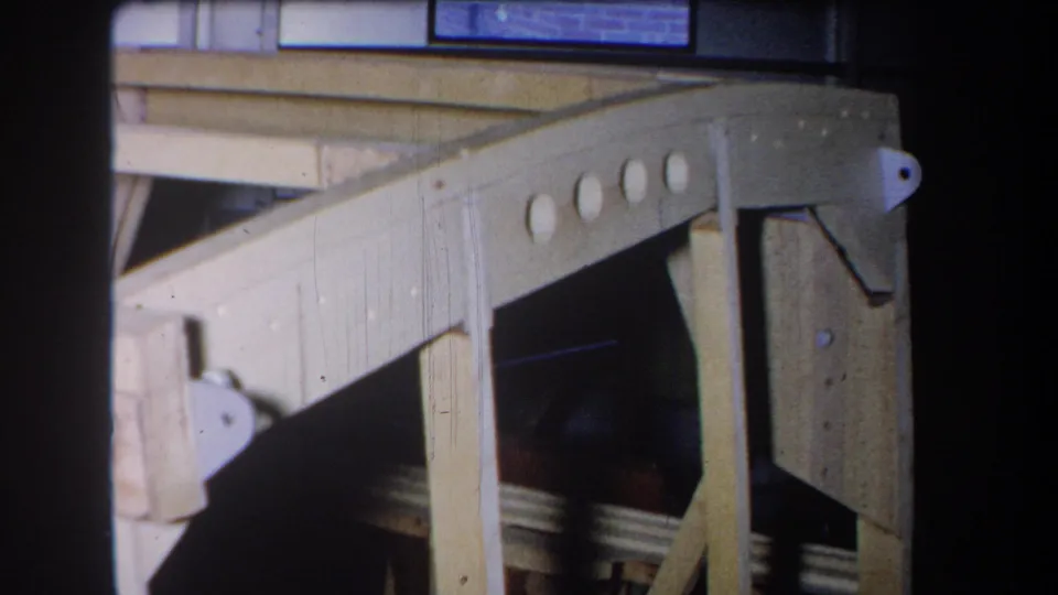 1965 Yucaipa close-up of an angled wooden frame section, showing round holes, posts, and a dark area behind the structure.
