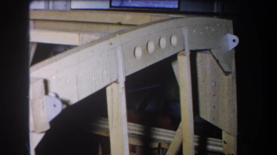 1965 Yucaipa home-movie frame showing the wooden side rail, circular openings, upright post, and workshop shadows.