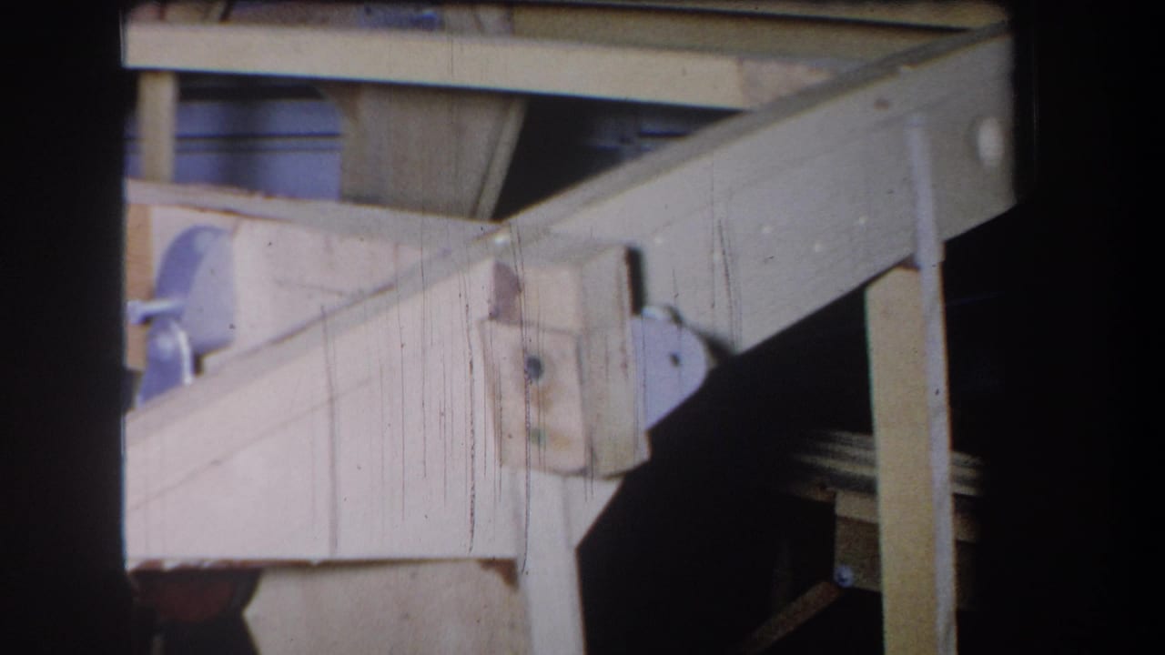 Wooden frame corner with diagonal beam, metal side plate, and vertical support.