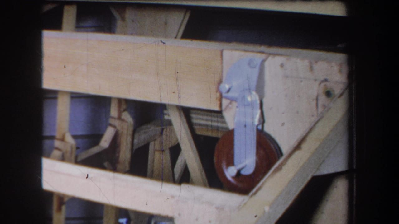 1965 8mm frame from Yucaipa showing pale lumber, diagonal supports, and a small red-brown wheel mechanism.