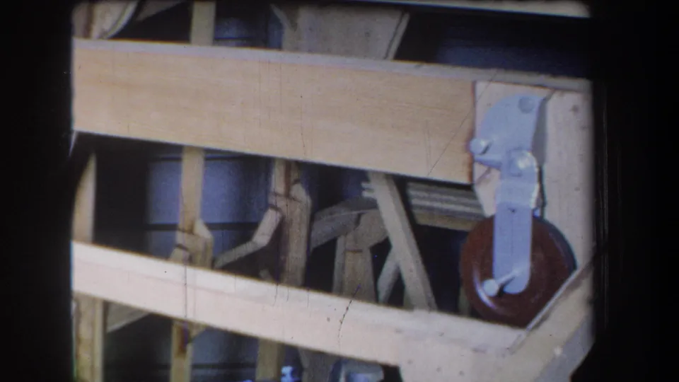 Close 1965 home-movie view of overlapping boards with a light blue bracket and red-brown wheel at the right edge.