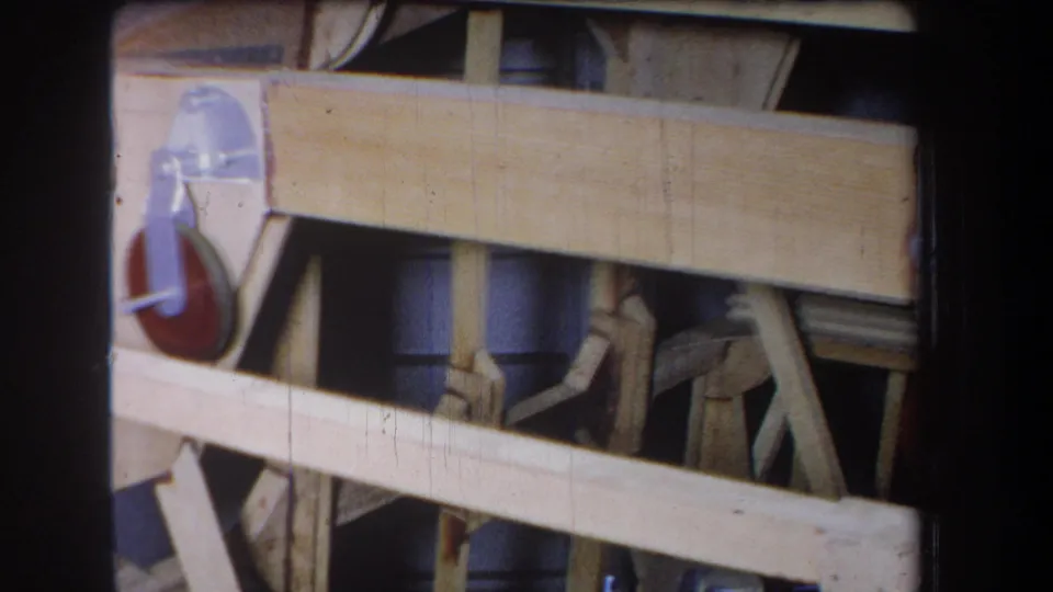 Yucaipa 1965 8mm frame showing pale lumber, diagonal bracing, and the edge of a bracketed wheel mechanism.
