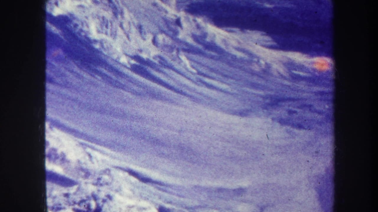 Snow-covered mountain slope with dark ridges and blue-purple film cast.