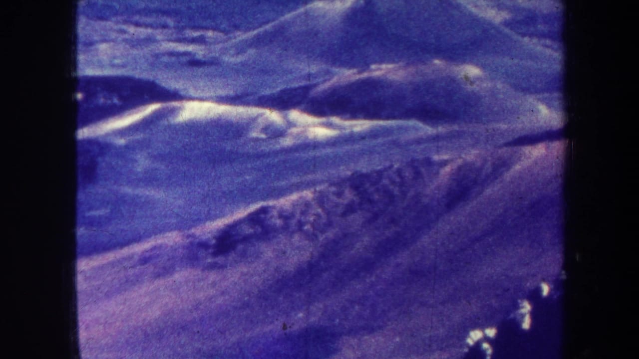 Distant mountain slopes and ridgelines with blue-purple film tint.