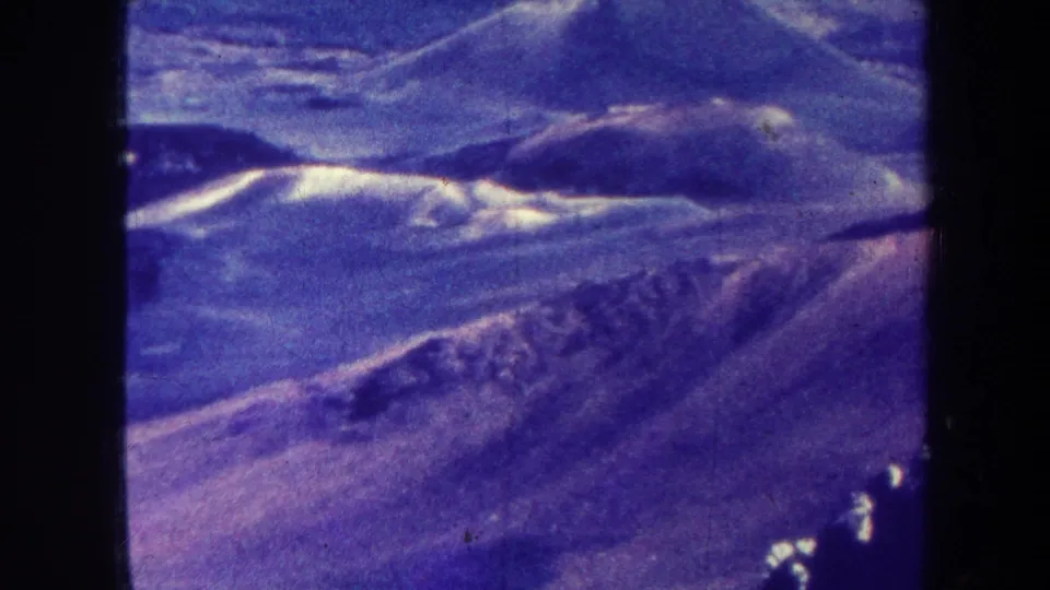 1967 Hawaii home-movie frame with distant ridgelines, soft focus, and aged blue-purple 8mm color.
