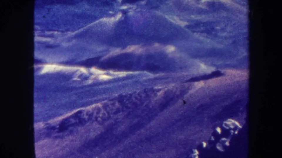 1967 Hawaii 8mm frame showing rugged mountain slopes with pale highlights, heavy grain, and color fading.