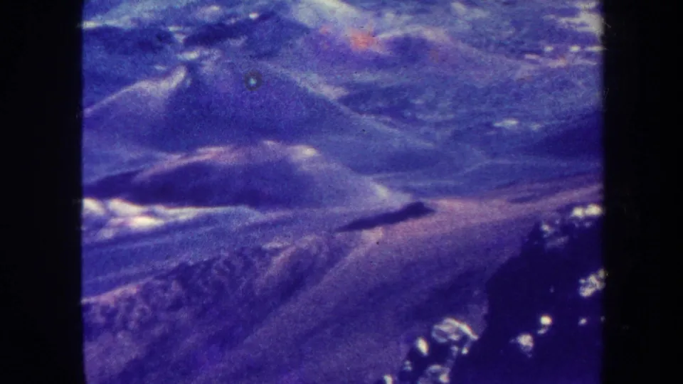 1967 Hawaii travel-film frame with mountain ridges, distant terrain, blue-purple fading, and visible 8mm borders.