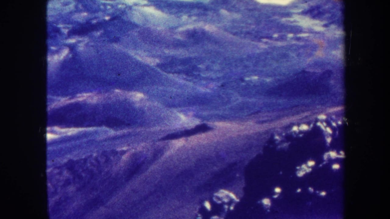 Purple-tinted aerial view of rugged hills and valleys within dark 8mm film borders.