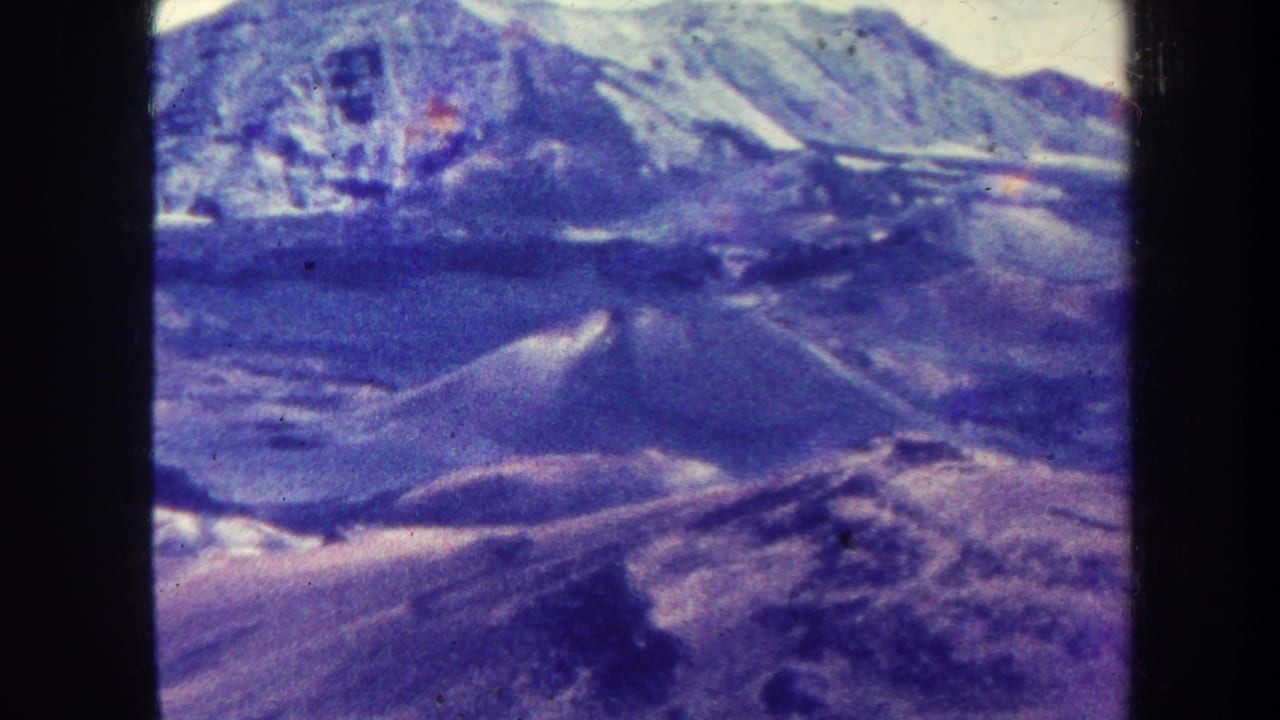 Hazy mountain range with pale or snow-dusted peaks and rocky foreground.