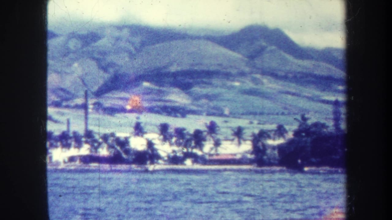 1967 Honolulu shoreline seen across blue water, with palms, white buildings, a smokestack, and mountain slopes beyond.