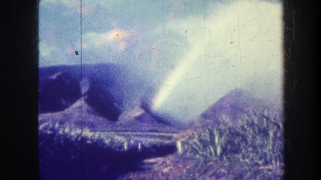 Honolulu, Hawaii 8mm frame with purple mountain slopes, pale cloud cover, bright diagonal light, and visible film wear.