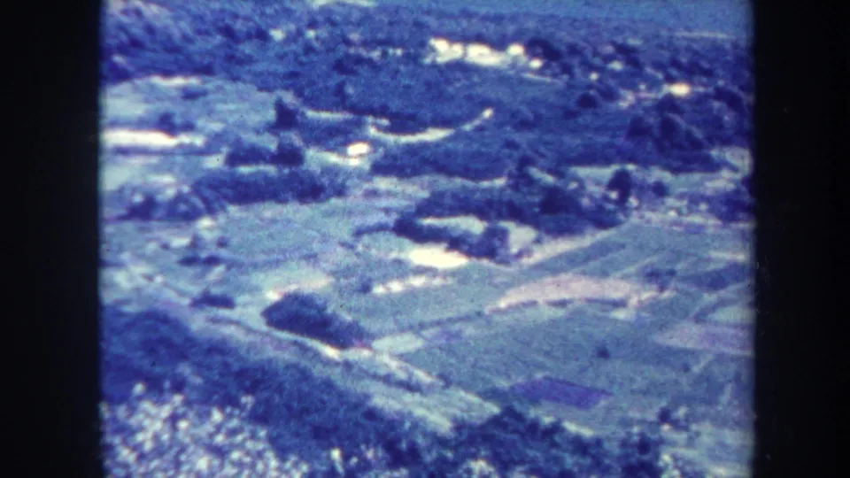 Soft 8mm frame of a Honolulu-area hillside landscape with fields, roads, vegetation, and small water features.