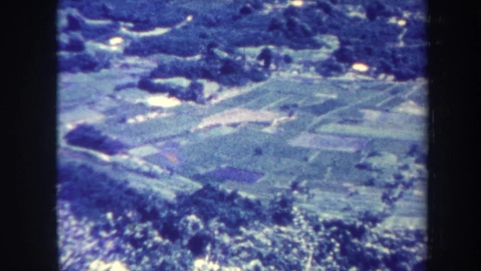 1967 Honolulu home-movie view over cultivated-looking fields, tree lines, roads, and reflective water patches.