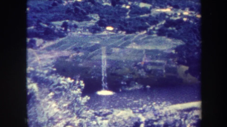 1967 Honolulu 8mm frame shifting from fields toward a waterfall pool surrounded by greenery.
