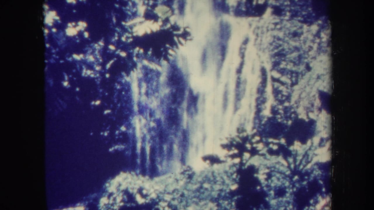 Tall waterfall framed by foliage and dark film border.