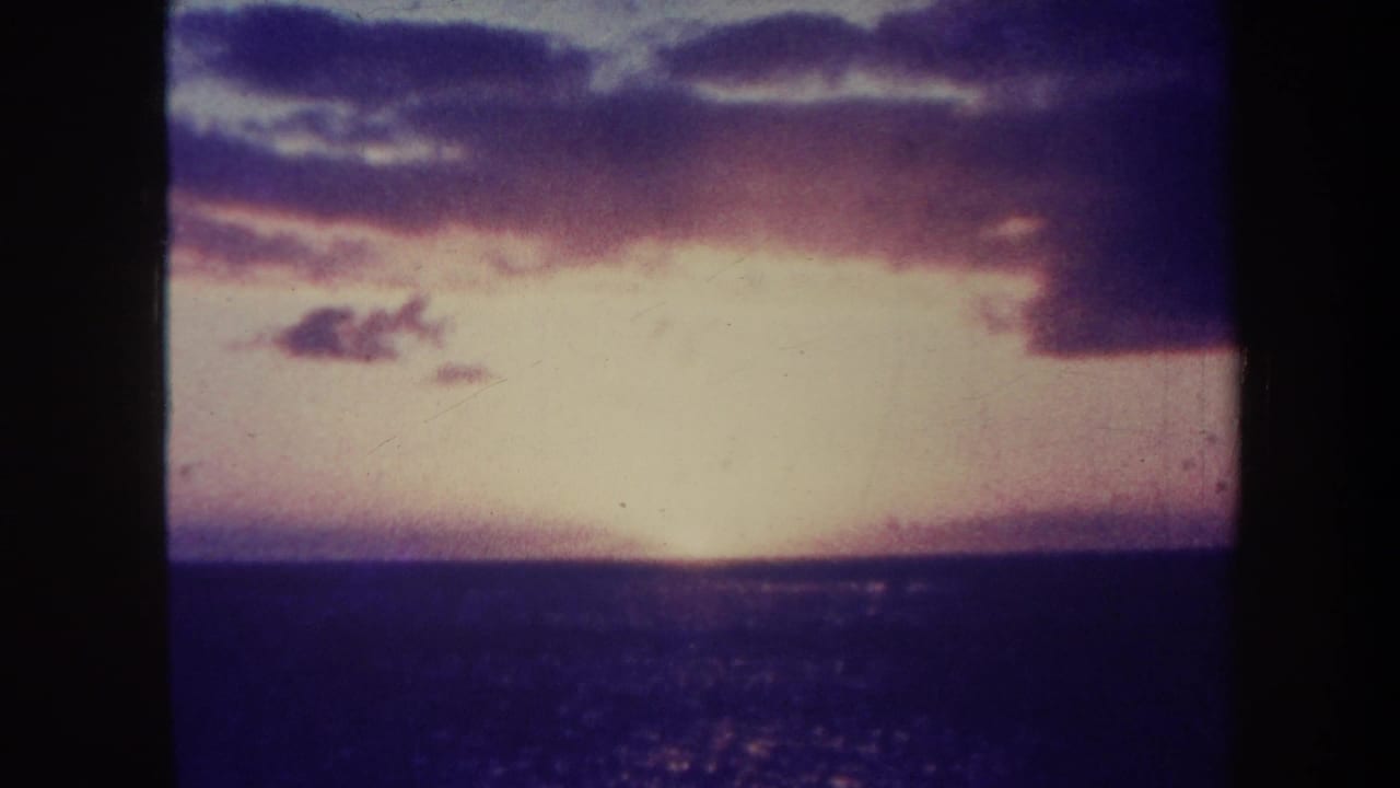 Purple-blue clouds over a dark ocean horizon at sunset.