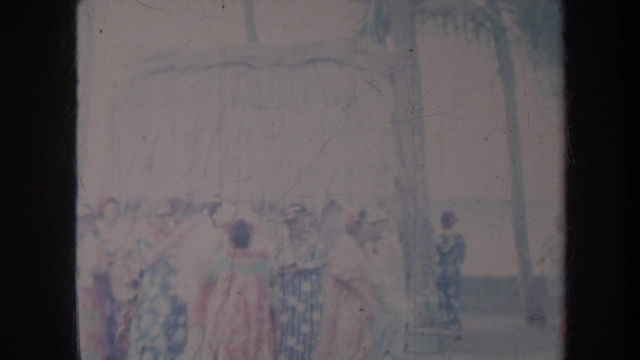 Group of women in patterned gowns and hats stand together outdoors.