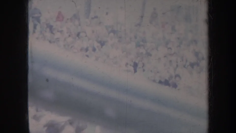 Soft 1967 Honolulu home-movie frame showing an indistinct outdoor crowd through a dark vertical frame with visible film wear.