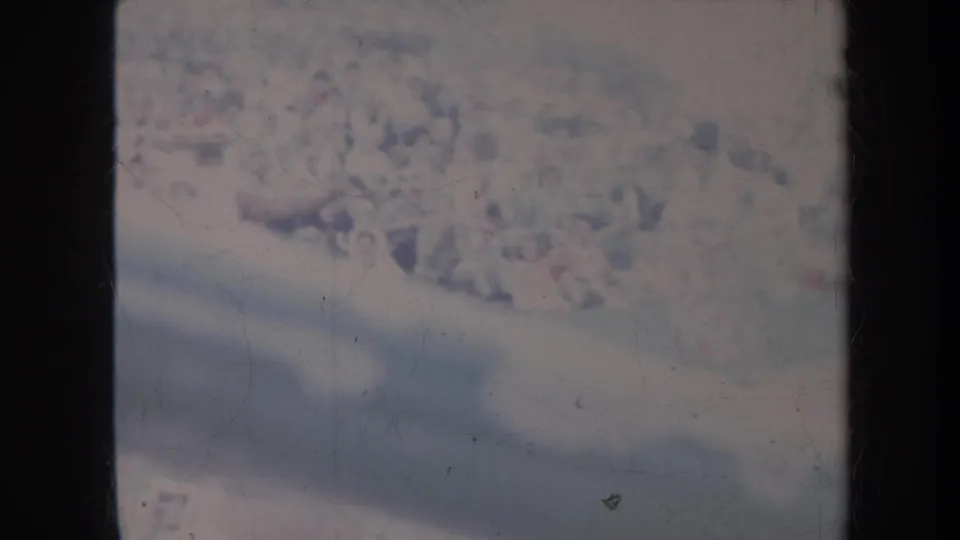 Soft 1967 Honolulu 8mm frame showing a distant gathering or crowd, with faded color, scratches, and dark scan edging.