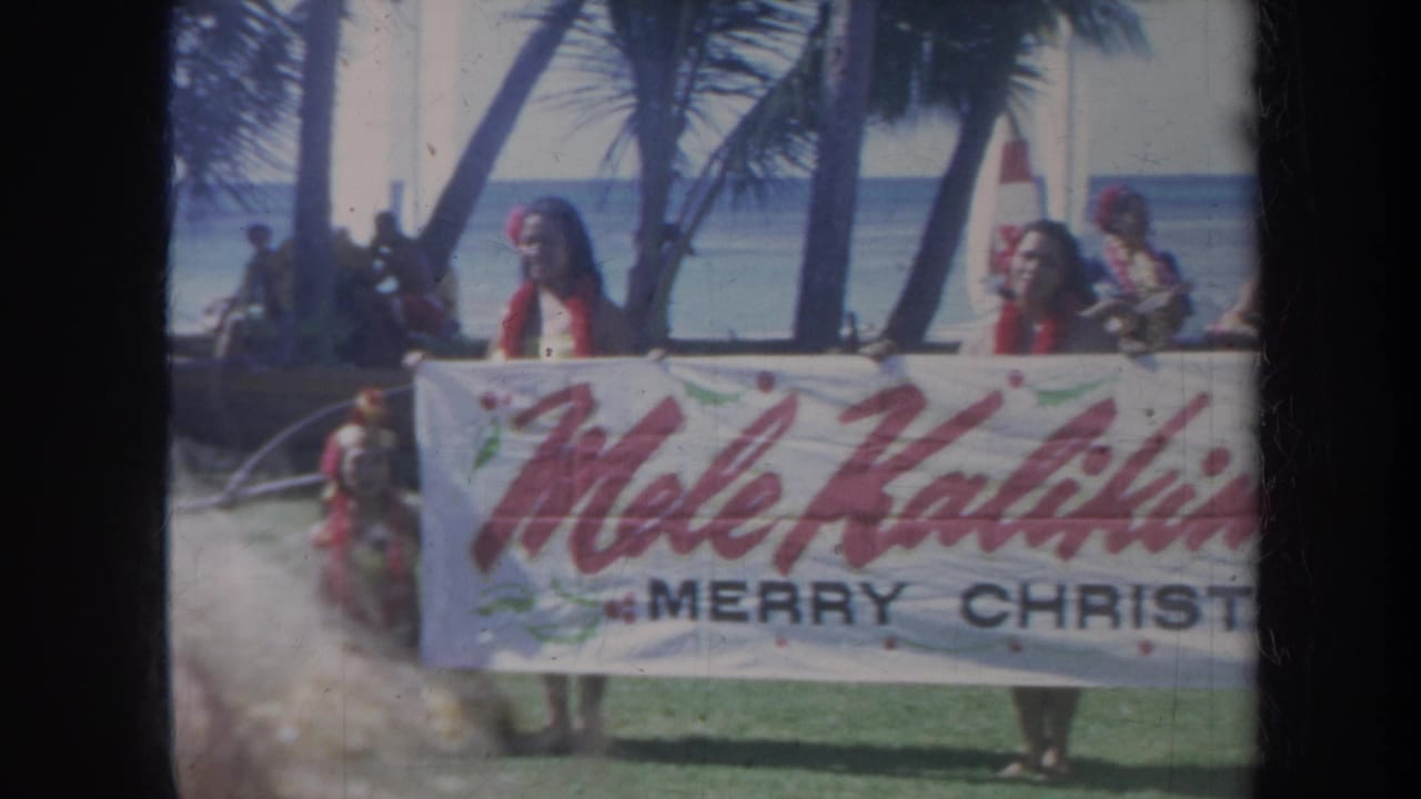 1967 Honolulu frame with women holding a Mele Kalikimaka Merry Christmas banner against a palm-lined beach and blue ocean backdrop.