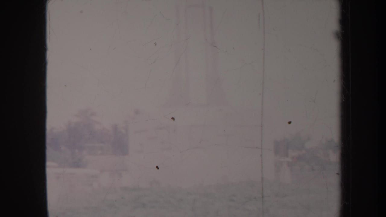 Hazy garden view with distant trees, railings, and pale sky on faded film.
