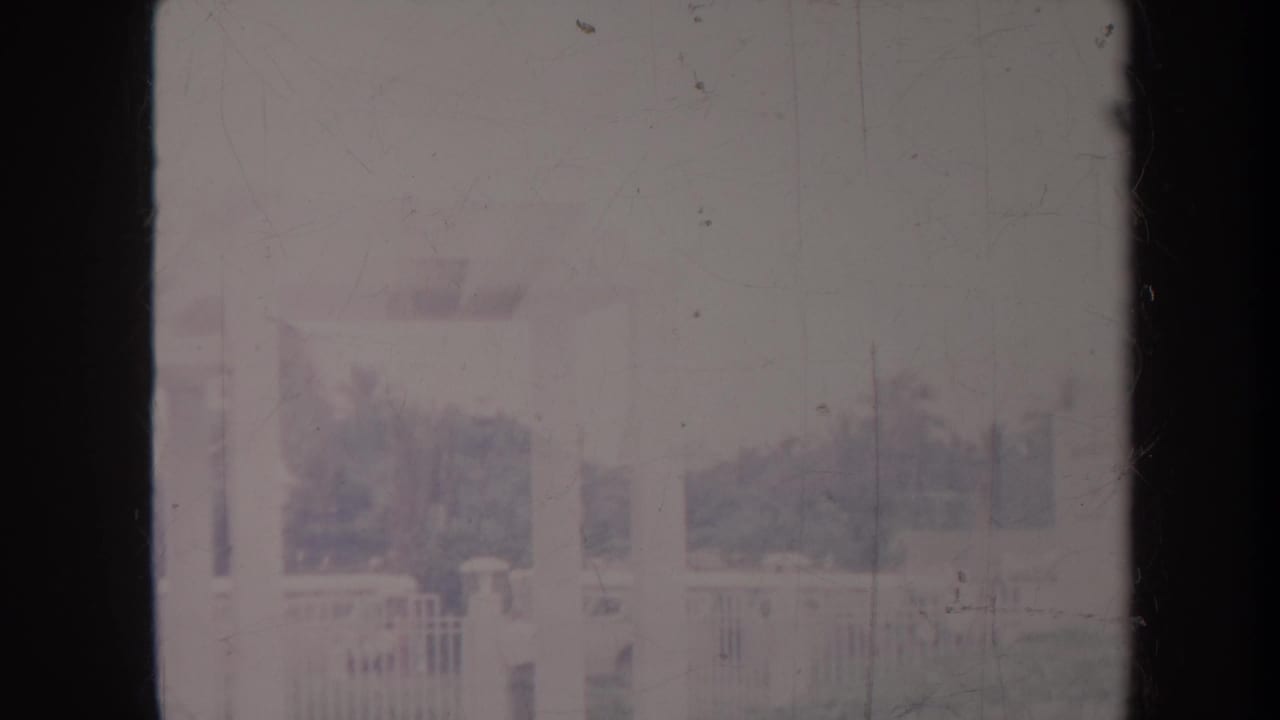 Distant landscaped grounds with a fence, trees, and a faint vertical structure.
