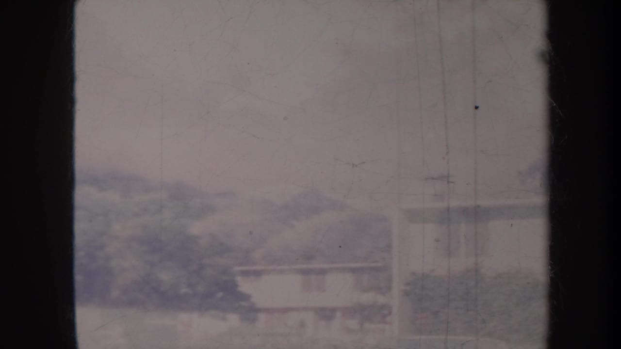 Blurred airport-side view with low buildings, trees, and a dark vertical contact-sheet border.