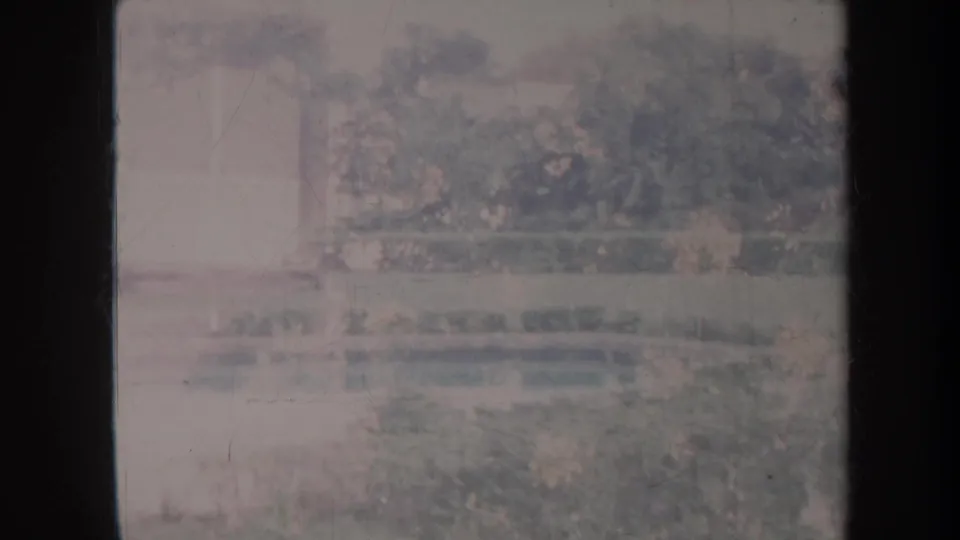 1967 Honolulu garden scene with a reflective pool, greenery, and washed-out 8mm exposure.
