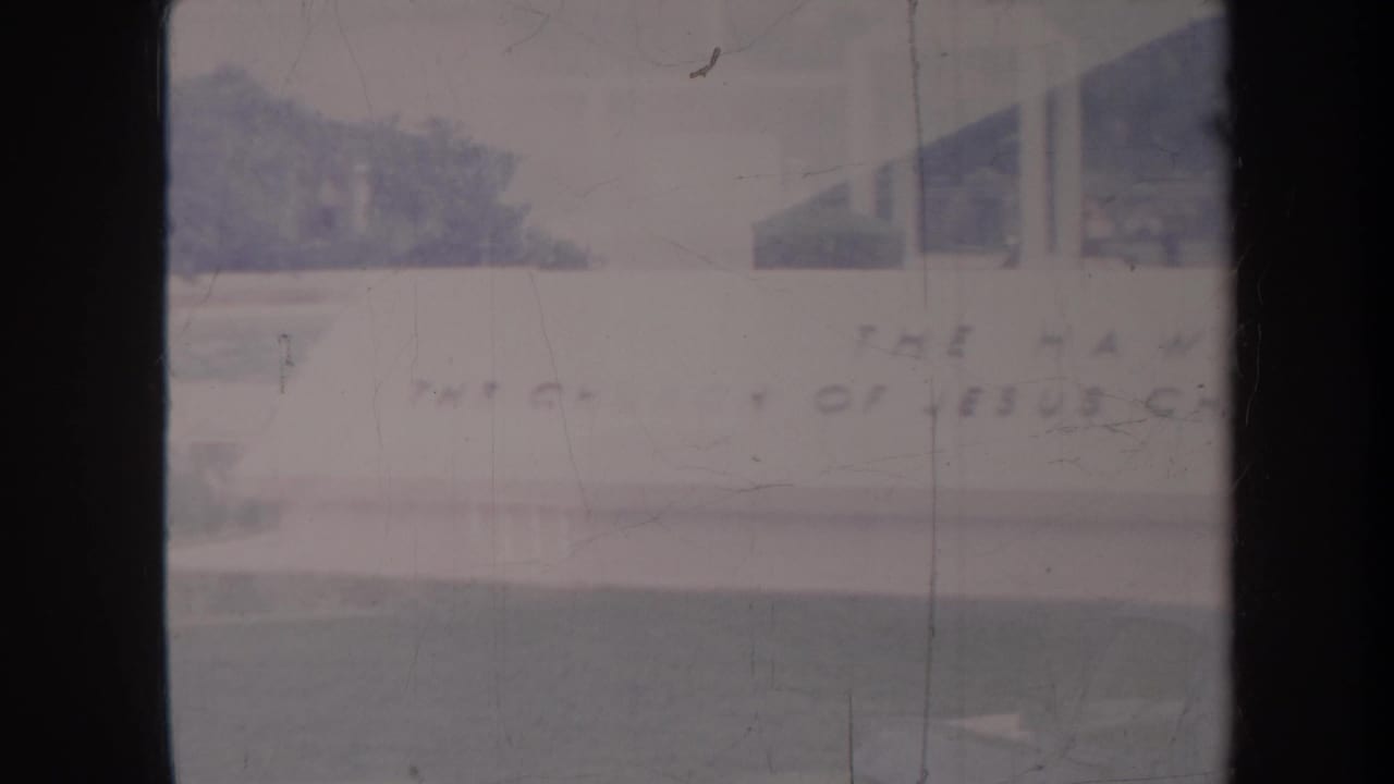 Faded exterior view of a church building with partial lettering and lawn below.