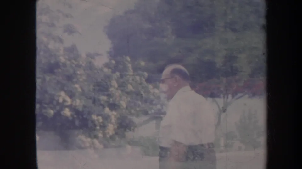 In the Honolulu yard scene, the older man walks past trees and flowering bushes, seen through the aged 8mm frame.