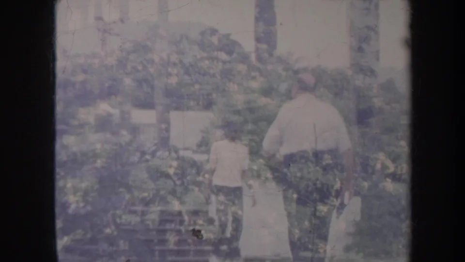 At the end of the Honolulu 8mm shot, the man walks away through the yard near shrubs, steps, and garden structures.