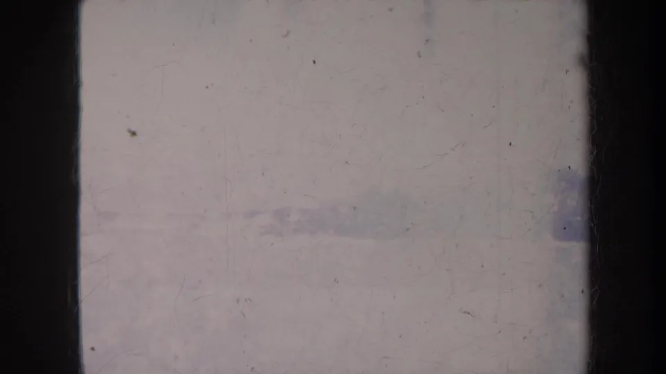1967 Honolulu 8mm frame with a hazy view past dark vertical framing toward trees, rooftops, and pale sky.