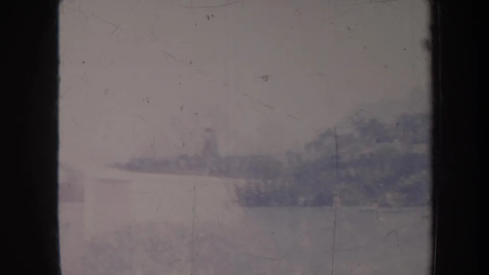 1967 Honolulu residential frame with soft rooftops, trees, and dark foreground bars in a faded 8mm scan.