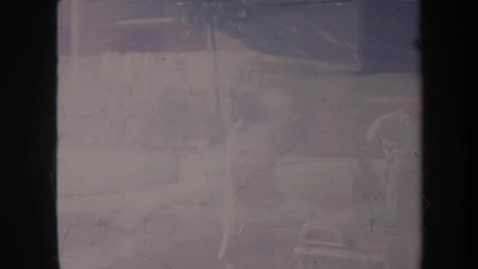 Faded Honolulu vacation frame with a person near a vehicle and palm-like foliage visible through heavy 8mm wear.