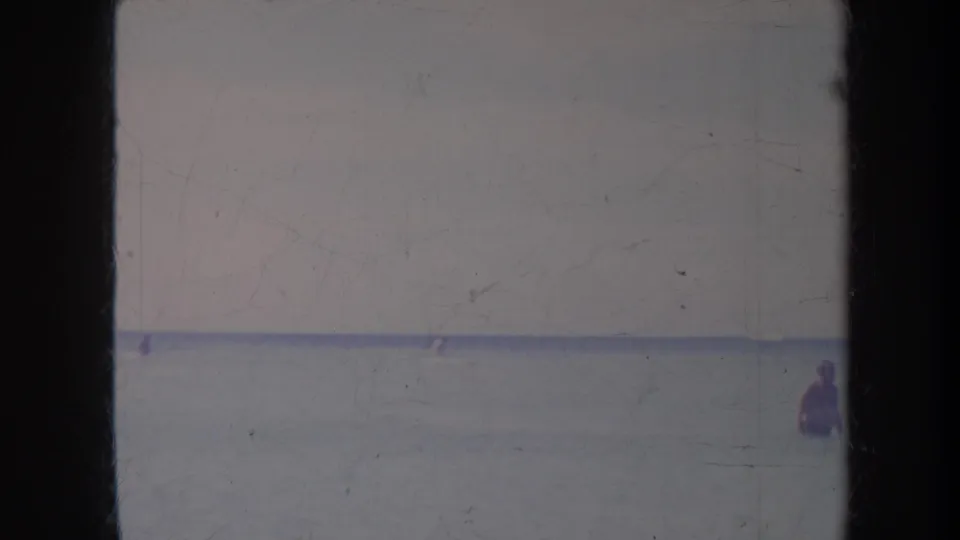 1967 Honolulu 8mm frame showing a distant person in the ocean near the right edge, with soft focus and film wear.