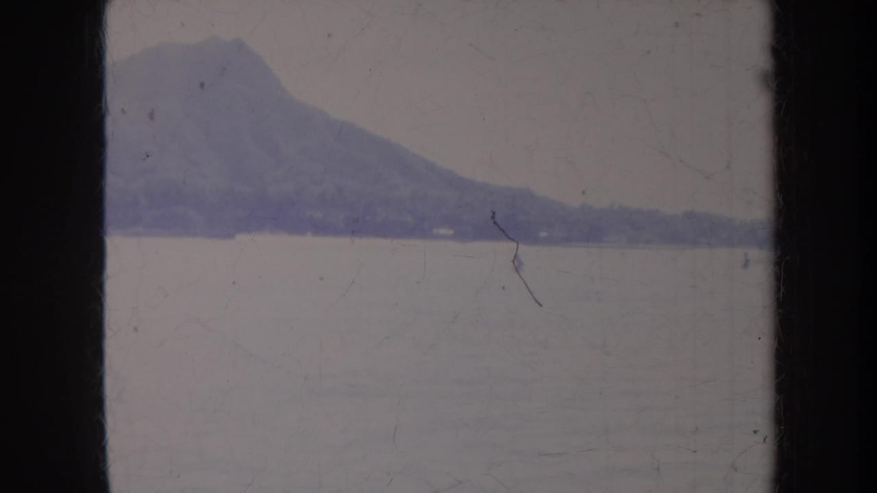 Distant mountain across calm water with faded 8mm film edges.