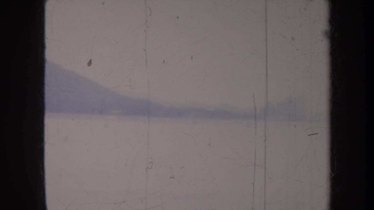 Low mountain ridge and shoreline seen through scratched film frame.