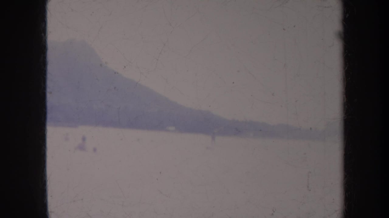 Distant mountain across pale water with tiny figures or craft barely visible.