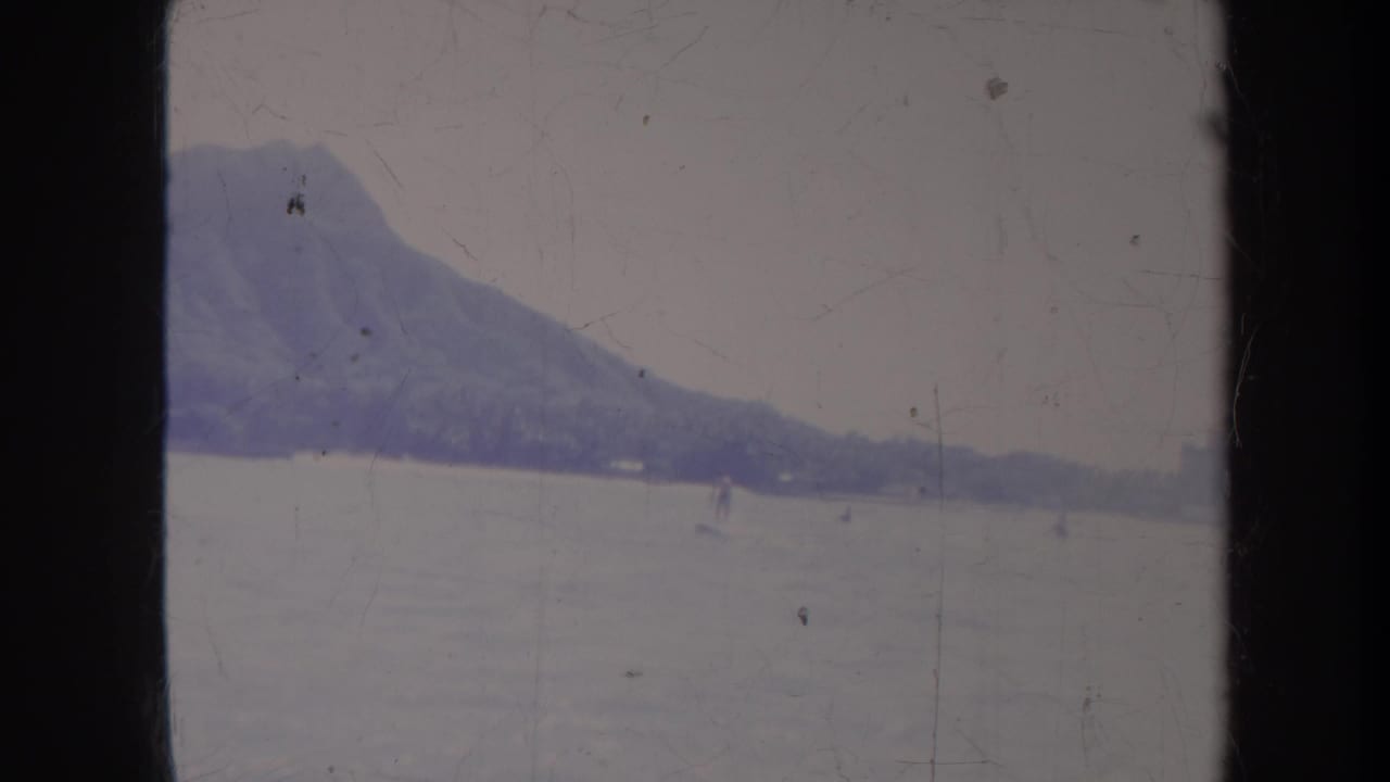 Diamond Head and shoreline appear beyond open water with a small skier-like figure.
