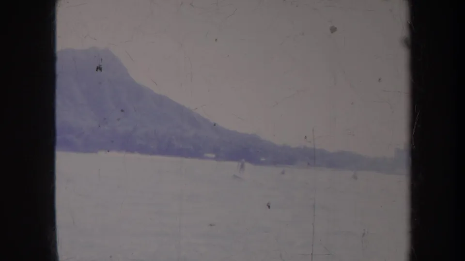 Faded 8mm Honolulu frame with Diamond Head in the background and a distant water-skier or figure on the water.