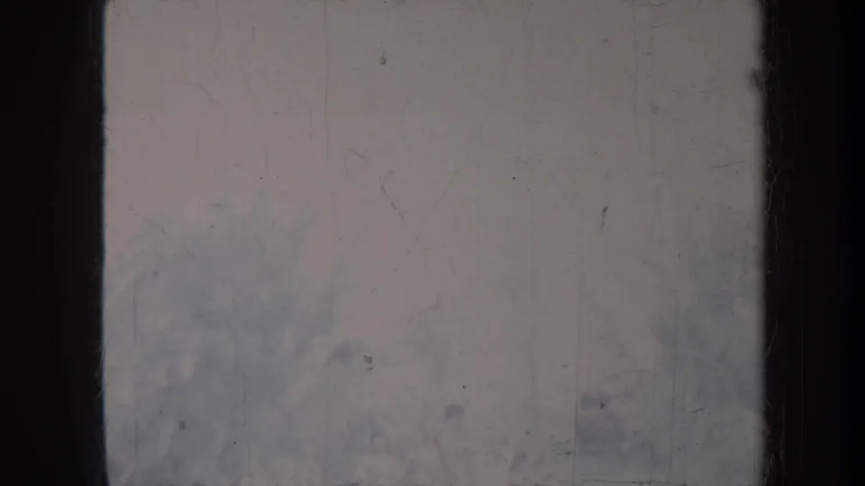 1967 Honolulu home-movie frame with washed-out exposure, dark film edge, scratches, and barely legible outdoor detail.