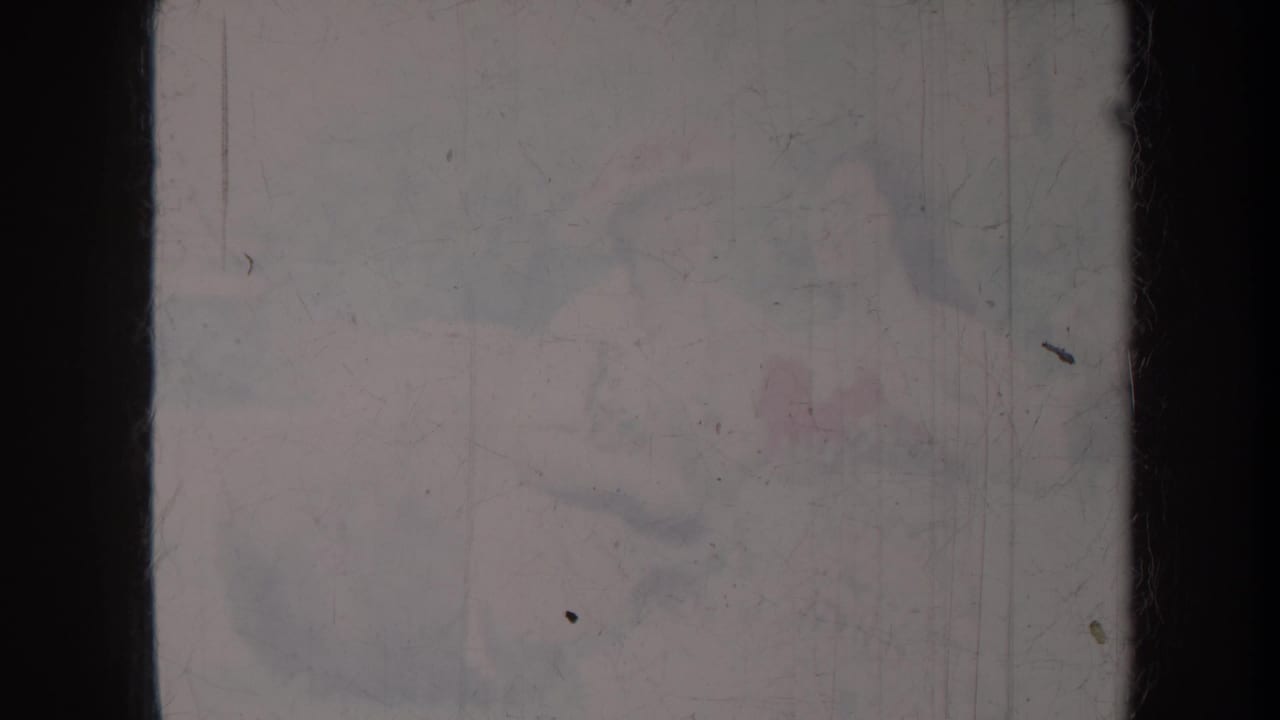Very faded frame with indistinct people and possible hand contact.