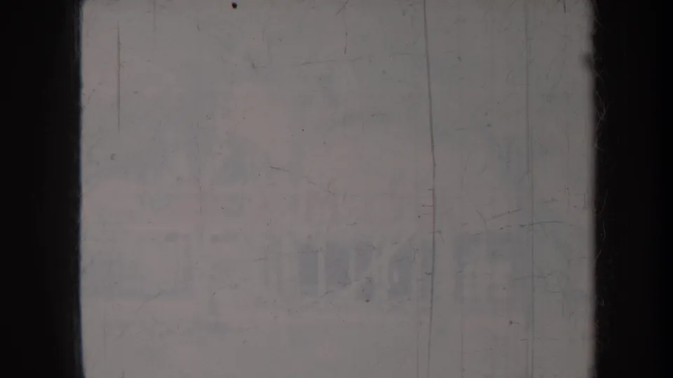 A faint 1967 Honolulu home-movie frame shows washed outdoor light and barely readable shapes through damaged 8mm film.