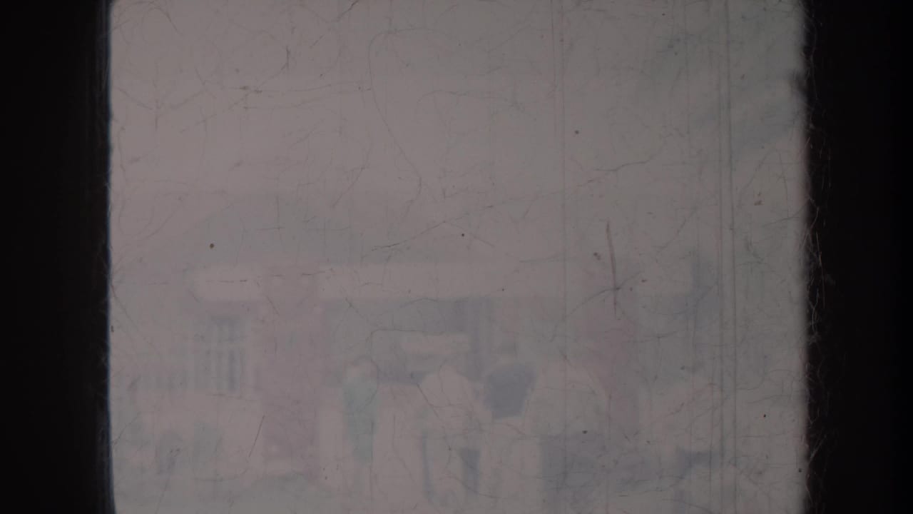 Faded outdoor view partly blocked by dark vertical edges, with indistinct forms beyond.